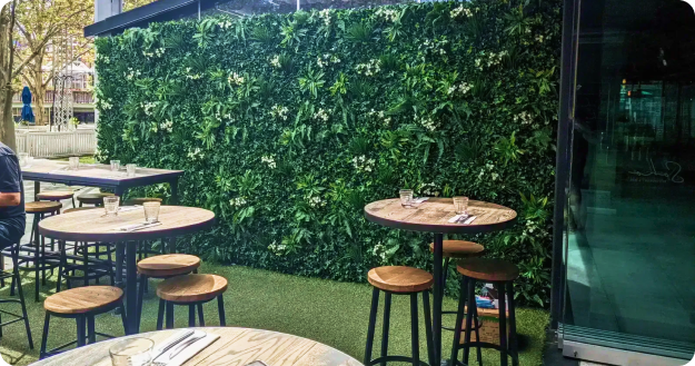 outdoor dining space with green plant wall and wooden furniture