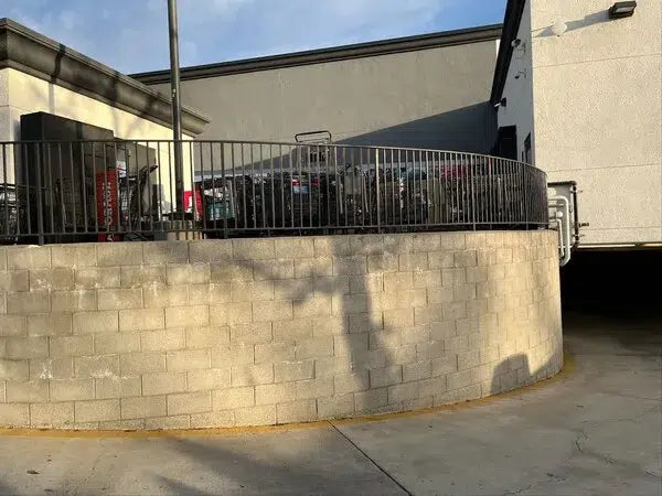 Black metal safety fence enclosing shopping cart area behind retail store second angle