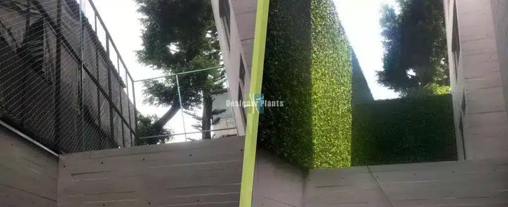An outdoor view of a modern building facade with a prominent green vertical hedge or living wall on the right, alongside a black metal fence on the left, with trees visible above and a bright yellow-green vertical structural element in the foreground.