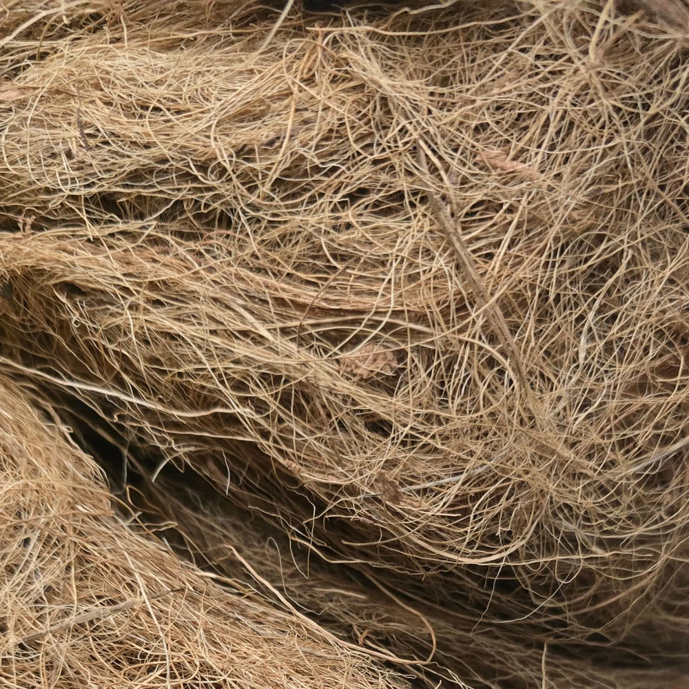 A close-up texture shot of a dense, tangled mass of natural brown coir or jute fiber.