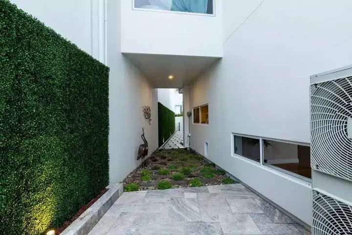 Modern house exterior with a neatly trimmed hedge and a small garden area.