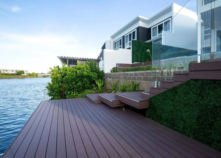 Modern house with a waterfront view featuring a wooden deck and outdoor furniture.
