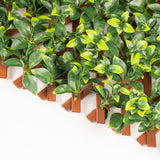 Artificial green leafy wall panel with wooden stakes on a white background
