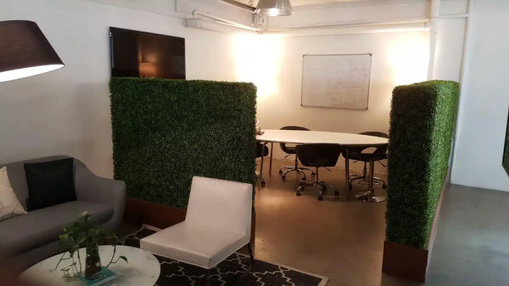 Modern office space with green partition walls, white chairs, and a conference table.