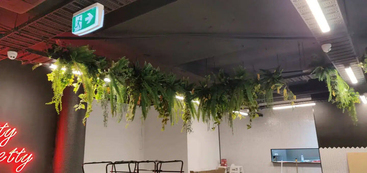 Ceiling with greenery and a neon sign in an indoor setting