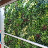 Artificial green wall panel with mixed foliage, vertical garden decor for indoor or outdoor spaces.