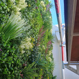 Outdoor artificial vertical garden wall with mixed green foliage and colorful plants.