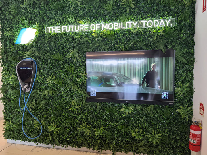 Green wall with a screen displaying a car and text 'The Future of Mobility, Today'.