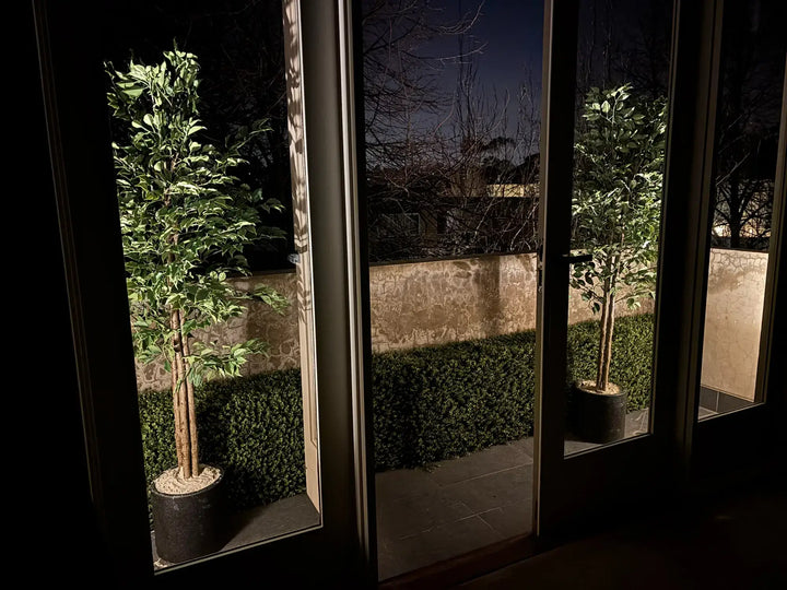 Artificial ficus tree styled outdoors in a landscaped residential setting