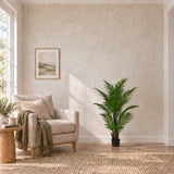 120cm artificial areca palm in its black pot beside a linen reading chair.