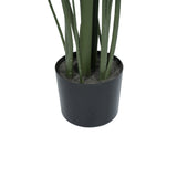 An artificial green plant with long, slender leaves in a matte black cylindrical pot filled with gray faux soil, shown against a plain white background.
