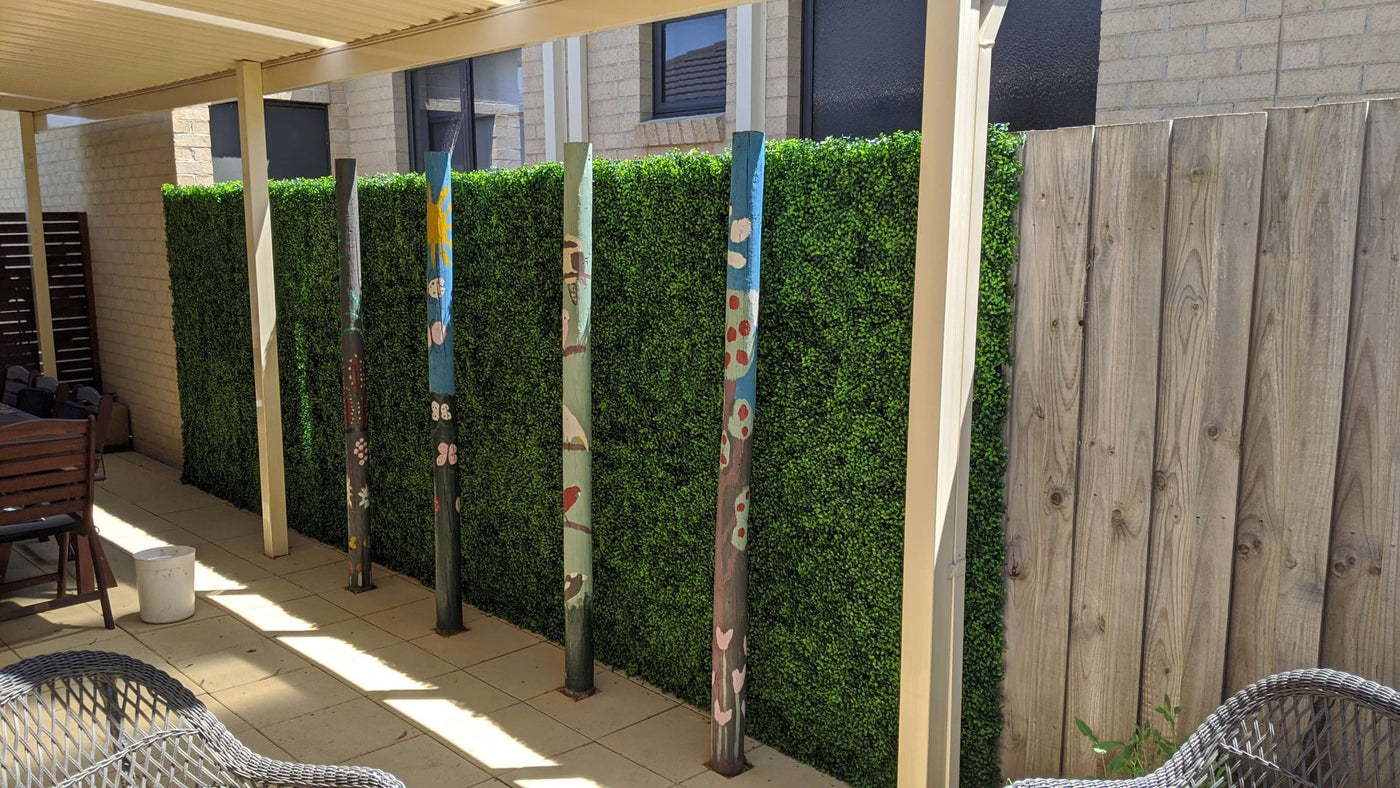 Outdoor patio area with a wooden fence and artificial greenery.