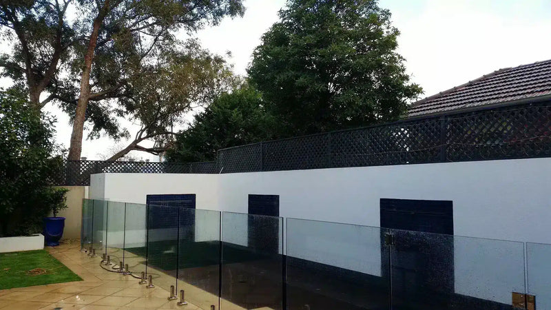 Before – A long extension fence above a pool had a range of boxwood panels installed to provide greater privacy in the homeowners rear yard.
