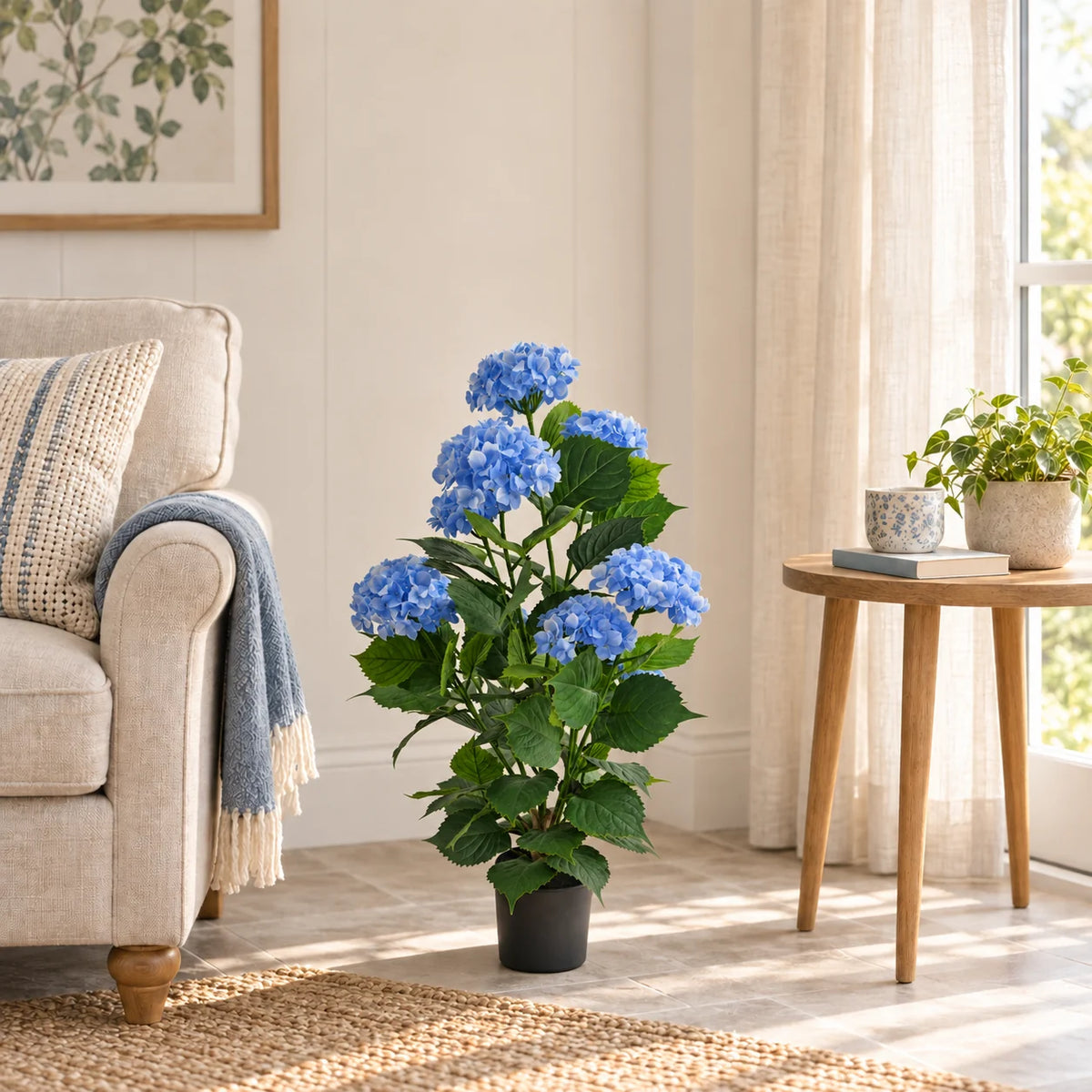 90cm blue artificial hydrangea in its black pot beside a sunroom armchair.
