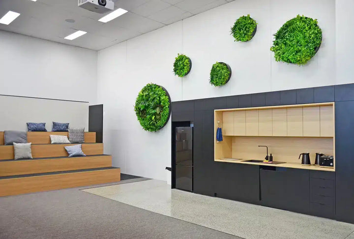 Modern office interior with green wall decorations and a kitchen area.