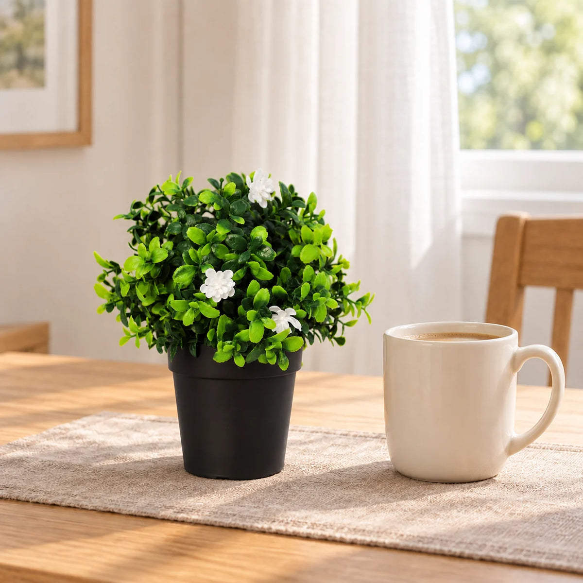 20cm artificial flowering boxwood in its supplied black pot on a breakfast table; tableware shown for styling.