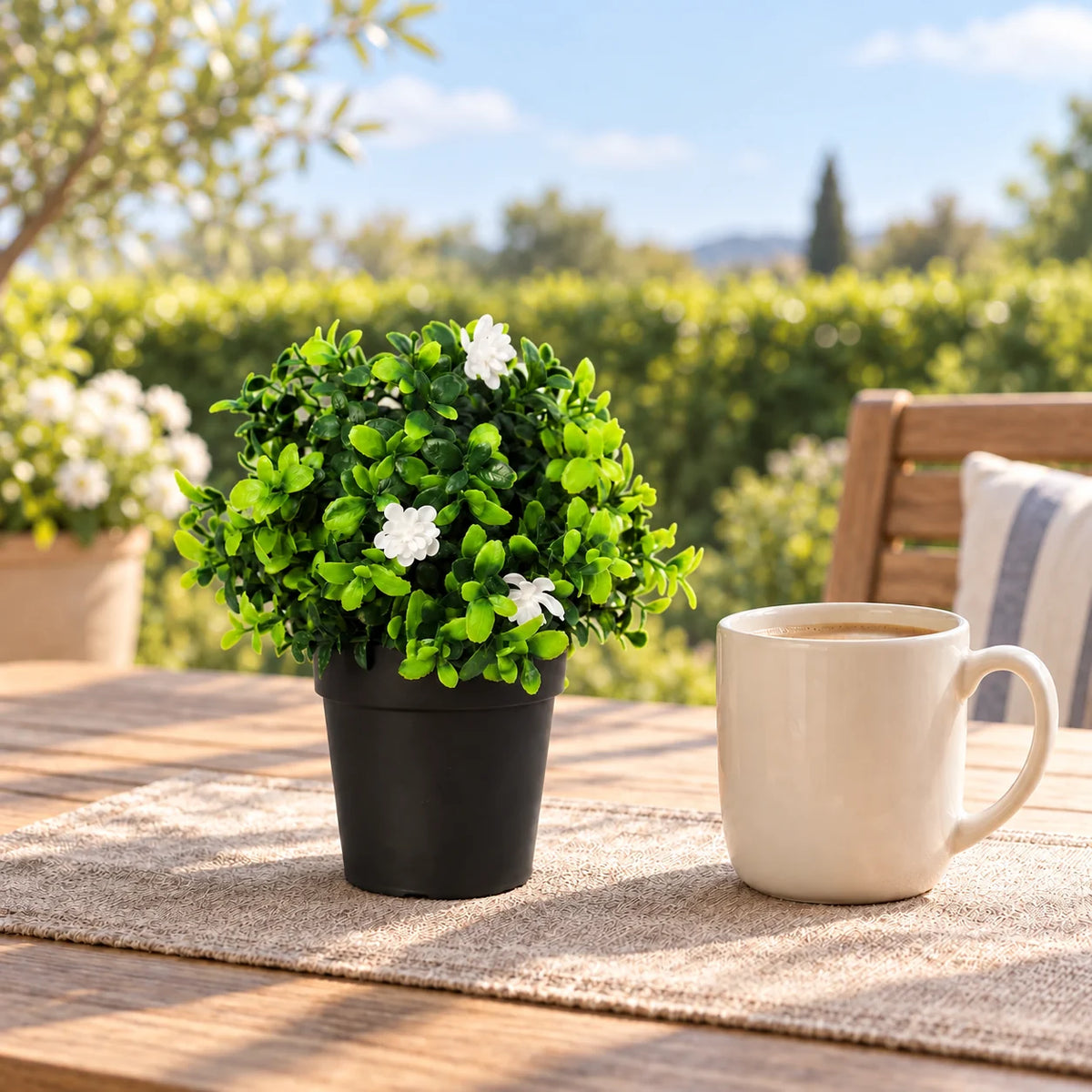 20cm potted artificial flowering boxwood beside a coffee mug on an outdoor patio table.
