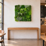 Forest Floor 1m x 1m artificial green wall panel styled above an oak console in a cafe. Furniture is not included.
