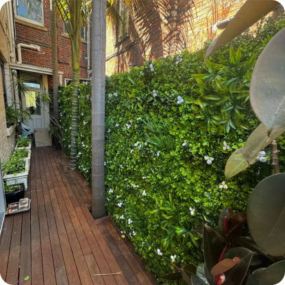 narrow outdoor garden with lush hedge and wooden pathway