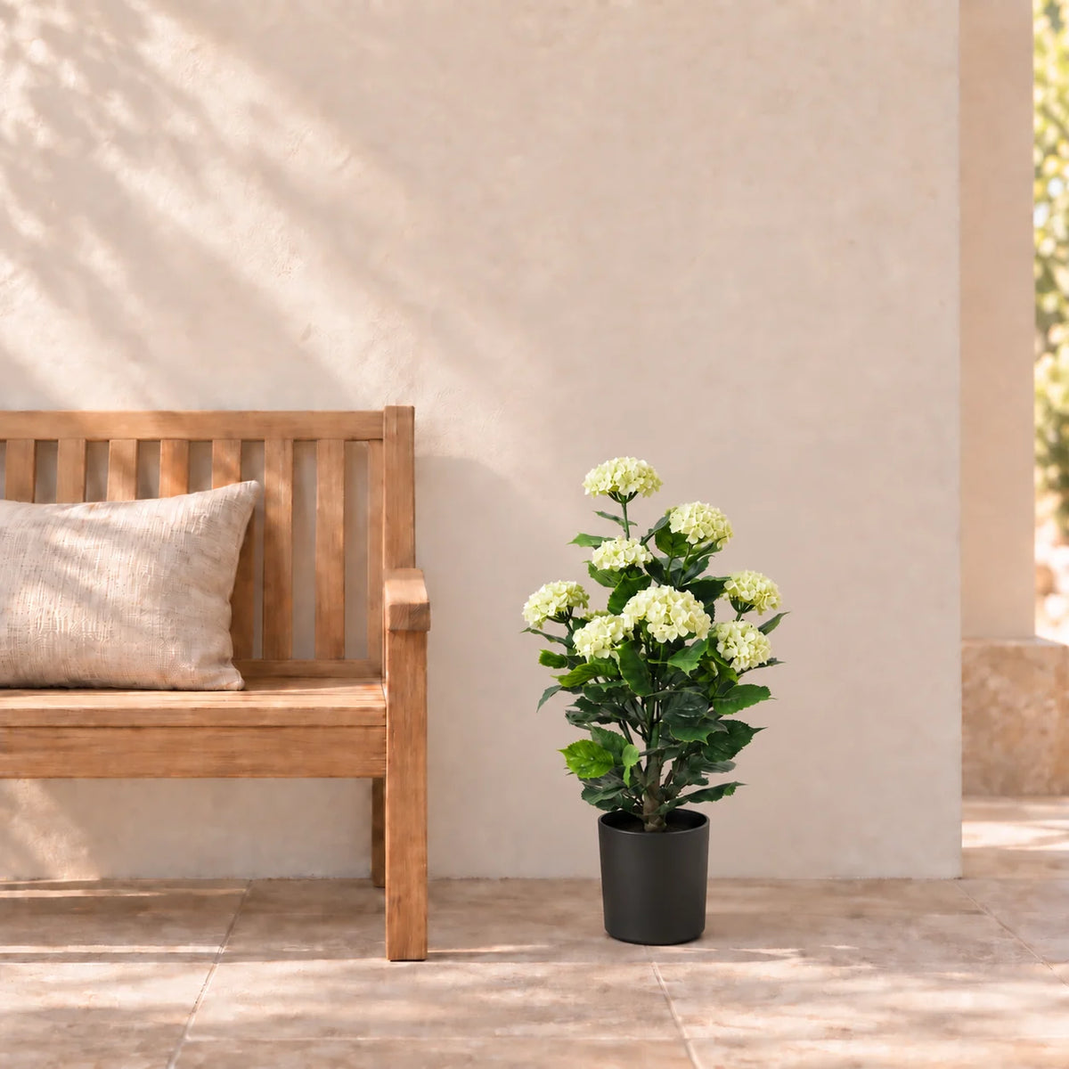 90cm artificial white hydrangea in its supplied black pot beside a terrace bench; furniture shown for styling.