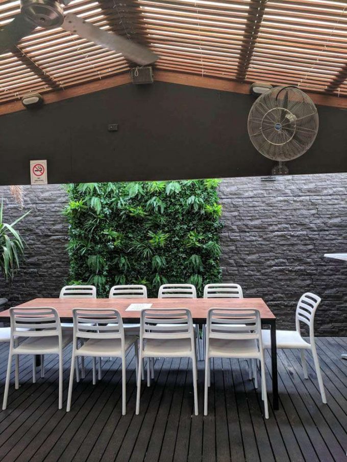 Outdoor cafe and seating area with green tropics on the wall
