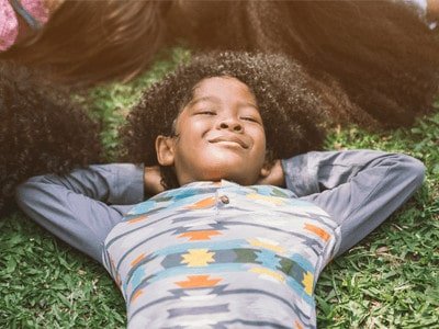 Pros and cons of real natural grass - child laying on grass