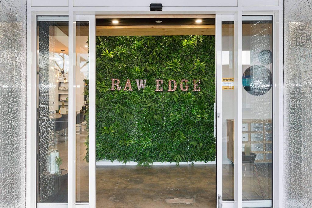 raw edge salon text in artificial green wall
