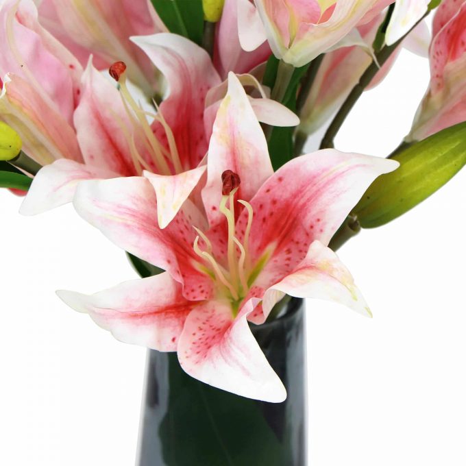 Pink artificial lily plants in glass vase